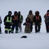 Un groupe de personnes vêtues chaudement attendent dans la neige. 