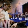 Cérémonie du feu d'une femme inuk. En arrière-plan, le premier ministre Brian Mulroney et les représentants autochtones sont assis au long d'une table pour signer l'accord.