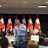 Pierre Poilievre debout avec un micro, entouré de personnes assises.