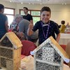 L'enfant lève un pouce en l'air devant ses maisonnettes pour insectes.