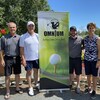 Cinq personnes posent ensemble près de l'affiche de l'omnium de golf.