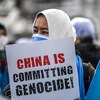 Une femme tient une affiche qui dénonce le « génocide des Ouïgours ».