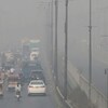 Des véhicules roulant sur une autoroute enveloppée par le smog.
