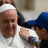 Un enfant place une main sur l'épaule du pape.