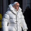 Une image à l'allure réaliste montrant le pape François vêtu d'un manteau matelassé blanc et portant un collier avec un crucifix.