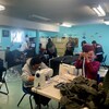 Des hommes autour de machines à coudre.