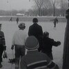 Jeunes vus de dos qui marchent vers la patinoire en tenant leurs patins dans leurs mains.