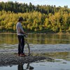 Un homme avec une canne à pêche près d'une rivière.