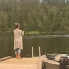 Une femme debout sur un quai tient une canne à pêche.