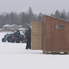 Une cabane de pêche installée sur une baie gelée.