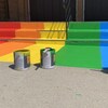 Des sceaux de peinture devant des marches colorées.
