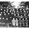 Une vieille photo en noir et blanc de jeunes écoliers autochtones en uniformes, assis en rangées.