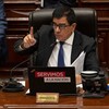 José Williams lève un doigt en parlant depuis son fauteuil du Parlement péruvien.