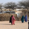Des personnes marchent dans un camp de déplacés internes sur un sol aride.