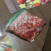 Un sachet en plastique qui contient de nombreuses petites fraises des champs est déposé sur une table.