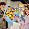 Deux jeunes adultes tiennent un globe terrestre dans leurs mains.                                