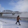 Un piéton marche le long de la rivière au centre-ville de Saskatoon, en Saskatchewan, lors d'une vague de froid le 25 janvier 2021.