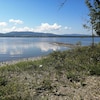 Une plage de galets et d'herbes hautes forme une pointe dans le lac Matapédia.