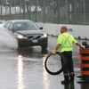 Un employé municipal barre la route sur le boulevard Lakeshore Ouest inondé.
