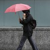 Une personne se protège de la pluie à l'aide d'un parapluie et d'un imperméable en marchant sur la rue Elgin, à Ottawa, le mardi 17 mai 2022 (archives).
