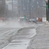 Des voitures projettent de l'eau sur une rue de Montréal.