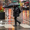 Une femme traverse une rue sous la pluie en hiver.