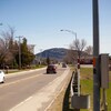 Boulevard passant dans un village. On voit une montagne en arrière-plan. 