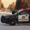 Une voiture de police arrêtée dans la rue à Calgary, des bandes jaunes bloquent le passage.