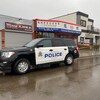 Deux véhicules de police sont stationnés devant des commerces dans le quartier chinois d'Edmonton.