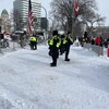 Des policiers en ligne entre les deux groupes devant le Palais législatif à Winnipeg. 