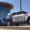 Une voiture de police de Surrey devant un édifice en verre. 