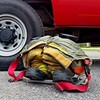 Un pantalon et des bottes de pompier sont posés sur le sol à côté d'un camion de pompier.