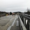 Des travailleurs avec un dossard sur le pont en construction.