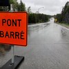 Une affiche indiquant "pont barré" sur une route. 