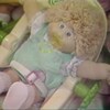 Une poupée Bout d'chou avec une suce dans un petit transat jouet.