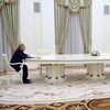 Vladimir Poutine est assis à gauche au bout d'une longue table blanche et Emmanuel Macron, à droite. Le somptueux décor est celui d'une salle du palais du Kremlin.