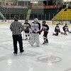Des jeunes joueurs de hockey et un arbitre sur la glace.