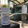 Une bouteille blanche affichant des informations sur les médicaments qu'elle contient.