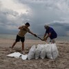 Deux personnes remplissent des sacs de sable.