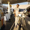 Un homme met de l'essence dans sa voiture à une station-service. 