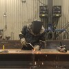 Un soudeur travaille une pièce de métal au chalumeau.