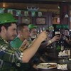 Des clients qui portent des chapeaux verts font un toast avec leurs verres de bière dans un pub irlandais.