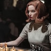 Le personnage Beth Harmon est attablé devant un jeu d'échecs.
