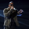 Le chanteur R. Kelly donne un spectacle sur un scène, un micro à la main.