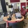 Un homme devant un micro, dans le studio de Radio Cité, à Edmonton.