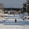 Vue d'ensemble sur la communauté : des maisons, un chemin enneigé et deux personnes qui marchent de dos sur le chemin. 