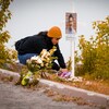 Une femme dépose des fleurs au pied de la croix.