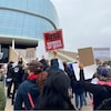 Des manifestants tiennent des pancartes devant un immeuble à Winnipeg le 1er octobre 2022. 