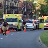 Des ambulances et des véhicules de police sur les lieux de la fusillade, alors que des voisins observent la scène depuis leur balcon.