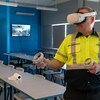 Luc porte un casque virtuel, l'air sérieux. Il est dans une classe d'enseignement.